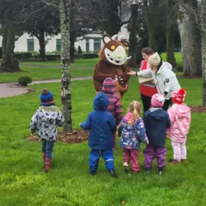 Gruffalo hanging out with a group of kids in the park.