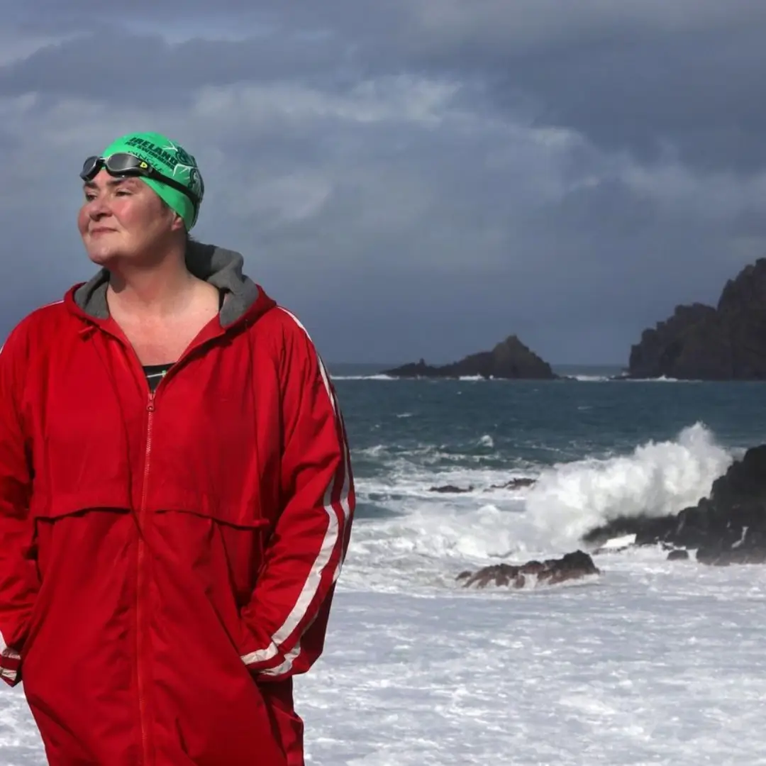 Nuala Moore outside standing beside the sea in a red dryrobe