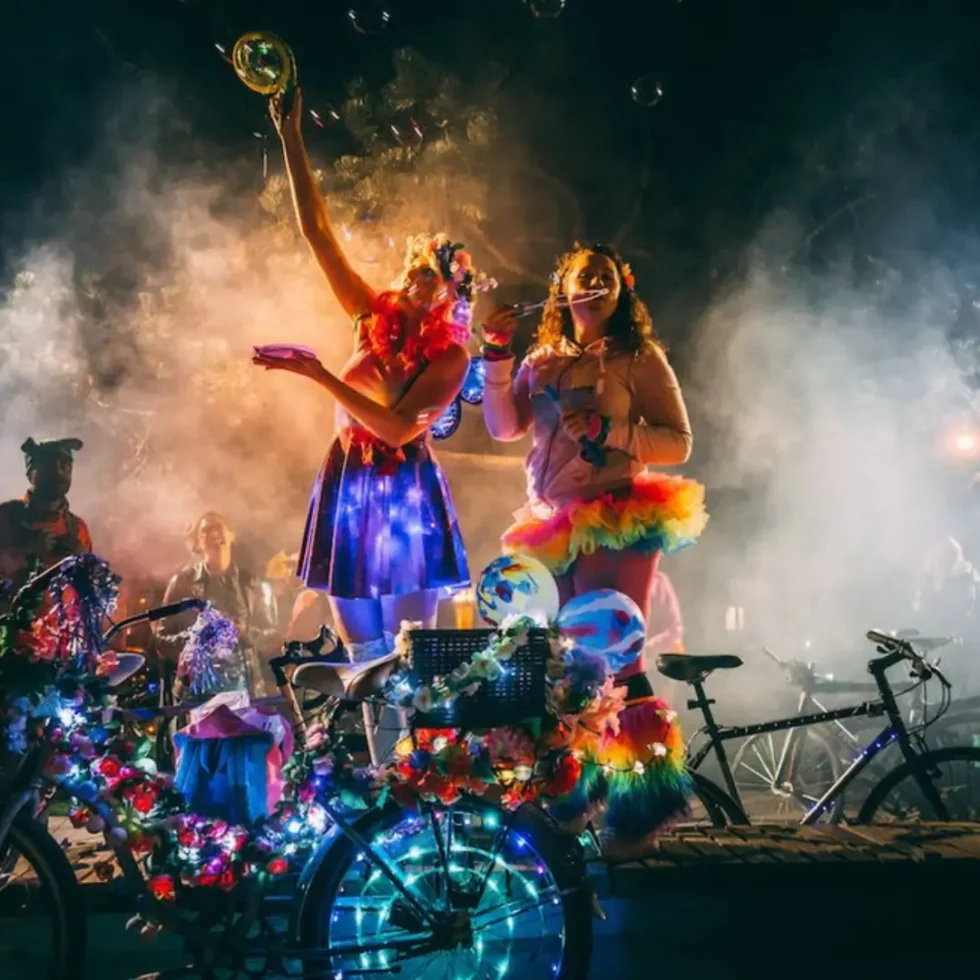 night time photo of girls dressed in colourful clothing and lights and bikes on the street