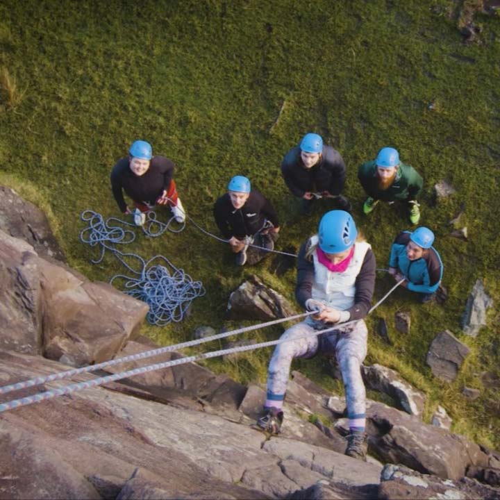 Repelling down a mountain with ropes and protective gear