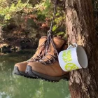 A pair of boots and a mug hanging from a tree
