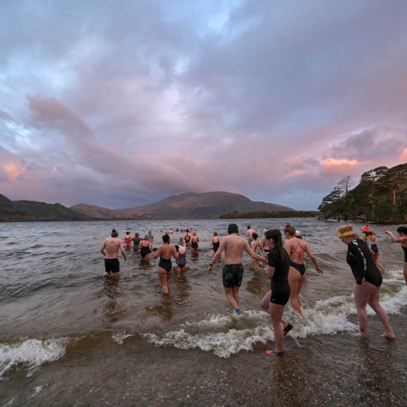 Swimmers running into the lakes of killarney under pink skies