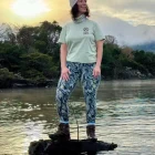 A lady standing in a lake wearing a sage wander wild tshirt