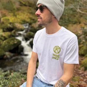 A man sitting near a river wearing a wander wild tshirt