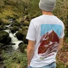 A man looking at a waterfall wearing wander wild merchandise